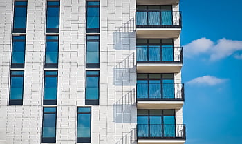 Contemporary urban apartment building with framed glass windows against clear blue sky. HD wallpaper