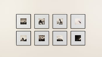 A minimalist display of framed mountain graphy on a plain wall. HD wallpaper