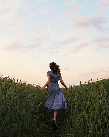 Woman in blue dress running through a green field at sunset, capturing a sense of dom and nature. HD phone wallpaper
