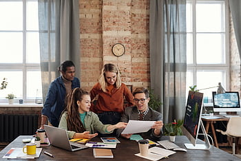 A diverse team of young professionals working on a business strategy in an urban office setting. HD wallpaper