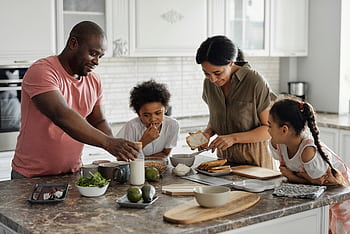 A joyful family enjoys preparing a healthy meal together in their modern kitchen. HD wallpaper