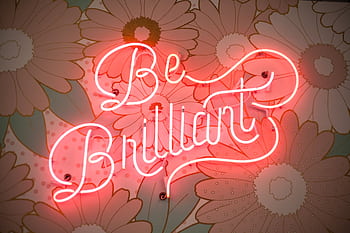 A glowing neon sign reading 'Be Brilliant' against a floral backdrop creates a vibrant and motivational atmosphere. HD wallpaper