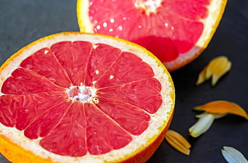 Close-up of juicy grapefruit halves showcasing vibrant red pulp on a dark background. HD wallpaper