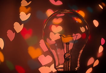 Light bulb with colorful heart-shaped bokeh creating a warm and romantic mood. HD wallpaper