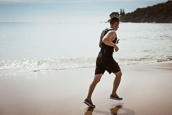 Man running along the beach enjoying fitness and dom by the ocean waves. HD wallpaper