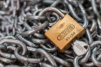 A detailed macro shot of a brass padlock with a key on heavy steel chains, symbolizing security and protection. HD wallpaper