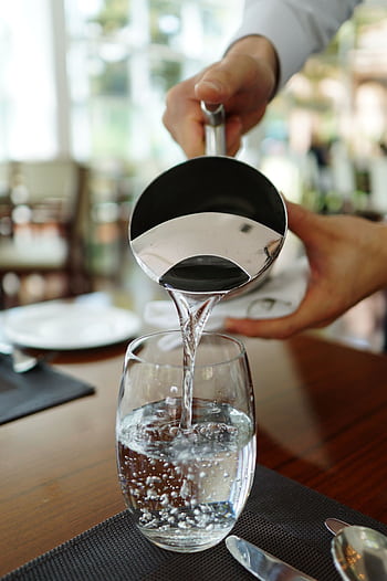 Close-up of water being poured into a glass in a restaurant setting. HD phone wallpaper