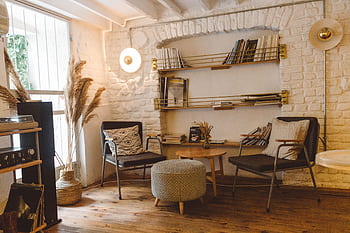 Inviting modern rustic living room featuring armchairs, an ottoman, and a stylish bookshelf. HD wallpaper