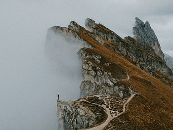 A solitary figure on the misty cliffs of the Dolomites in Italy, an epic autumn landscape. HD wallpaper