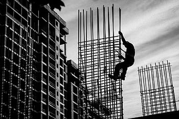 Black and white silhouette of a construction worker climbing steel rods on a building site. HD wallpaper