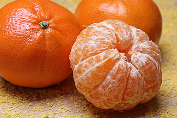 Close-up of fresh clementines and a peeled segment on a textured background. HD wallpaper