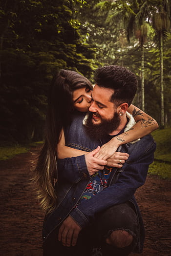 A couple embracing lovingly in a lush forest, showcasing youthful affection. HD phone wallpaper