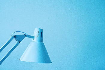 Close-up of a minimalist desk lamp against a light blue background with ample copy space. HD wallpaper
