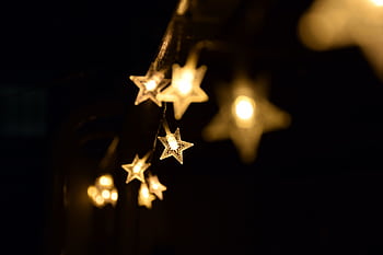 Warm star-shaped fairy lights hanging elegantly in the night, creating a festive ambiance. HD wallpaper
