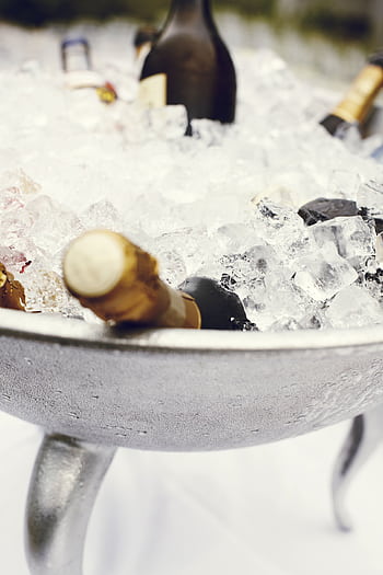 Close-up of chilled champagne bottles in an ice bucket, perfect for celebrations and parties. HD phone wallpaper