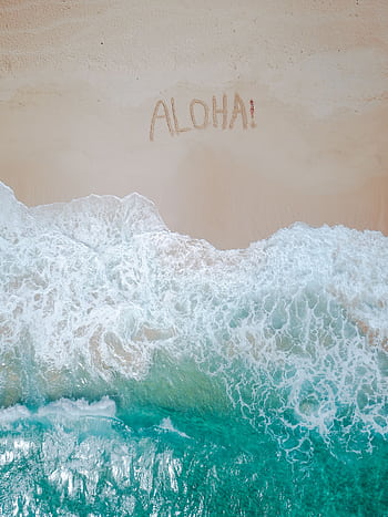 A serene aerial shot of a tropical beach with 'Aloha' written in the sand and waves crashing ashore. HD phone wallpaper