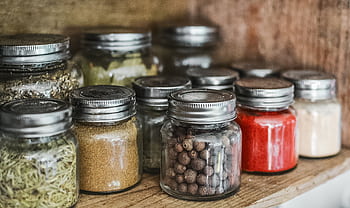Close-up of assorted spice jars with various herbs on a kitchen shelf, showcasing colorful culinary ingredients. HD wallpaper