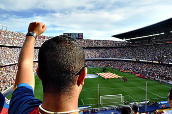 A passionate football fan cheers among a crowd at a bustling stadium, creating an electrifying atmosphere. HD wallpaper