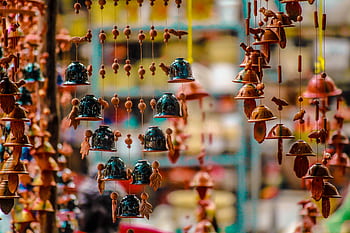Vibrant hanging bells and ornaments in a pottery market stall, showcasing cultural artistry. HD wallpaper