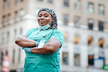Proud nurse with arms crossed, in uniform, outdoors, urban setting, showing confidence and professionalism. HD wallpaper