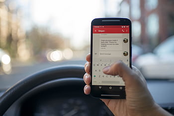 Close-up of a person texting on a smart while driving a vehicle, highlighting distracted driving. HD wallpaper