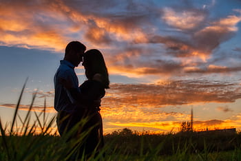 Silhouette of a couple embracing against a vibrant sunset sky, capturing romantic and serene moments. HD wallpaper