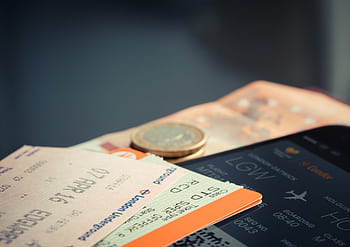 Airline ticket with euro coins and smart displaying flight details. HD wallpaper