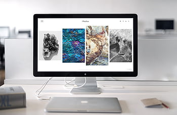 A contemporary office desk setup featuring a sleek computer monitor displaying abstract artwork. HD wallpaper