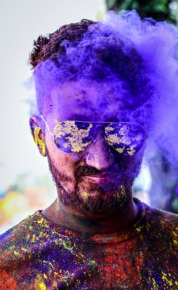 Vibrant portrait of a man celebrating Holi with colorful powder and sunglasses outdoors. HD phone wallpaper