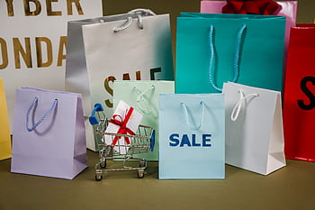 A mix of colorful shopping bags and a small cart displaying a discount gift. HD wallpaper