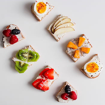 An artistic flat lay featuring a variety of fruit-topped cream cheese crackers, perfect for breakfast or brunch. HD phone wallpaper