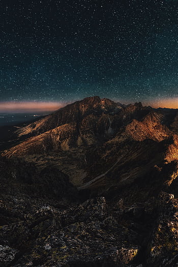 Stunning starry night sky over rugged mountains, perfect for nature lovers. HD phone wallpaper