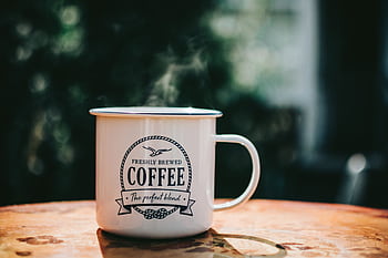 Warm coffee mug steaming on a rustic table, evoking cozy morning vibes. HD wallpaper