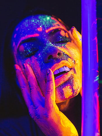 Close-up portrait of a woman with luminous neon face paint under a blacklight, showcasing vibrant colors. HD phone wallpaper