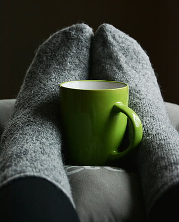 Warm and cozy indoor scene with a green mug between gray wool socks, perfect for relaxation. HD phone wallpaper