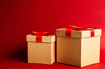 Two gift boxes with red ribbons on a vibrant red background. HD wallpaper