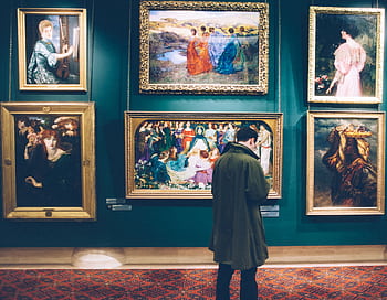 Person views classic artworks in an elegant gallery setting, exploring art history. HD wallpaper