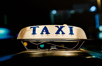 Close-up view of an illuminated taxi sign in a bustling city at night. HD wallpaper