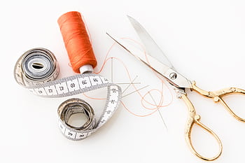 of sewing essentials: scissors, thread, needles, and tape measure on a white background. HD wallpaper