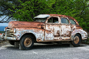 A heavily rusted vintage car abandoned outdoors, surrounded by nature. HD wallpaper