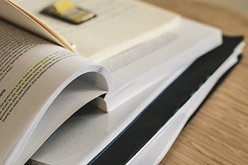 A pile of open books on a table, ideal for study and research themes. HD wallpaper