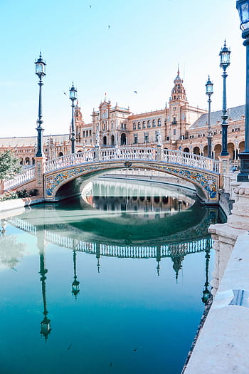 Explore the stunning architecture of Plaza de España in Seville, featuring a beautiful bridge and canal reflection. HD phone wallpaper