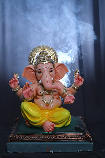 Colorful Ganesha statue with incense smoke, embodying Hindu spirituality and grace. HD phone wallpaper