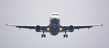A commercial airliner captured head-on, preparing to land against a cloudy sky. HD wallpaper