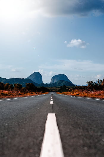 Long straight road leading to distant mountains under a bright blue sky. HD phone wallpaper