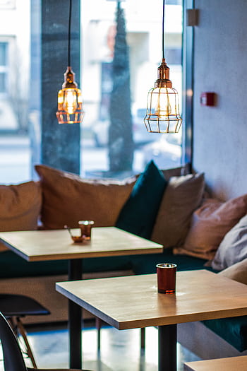 Warm and inviting cafe interior featuring modern pendant lighting and comfortable seating. HD phone wallpaper