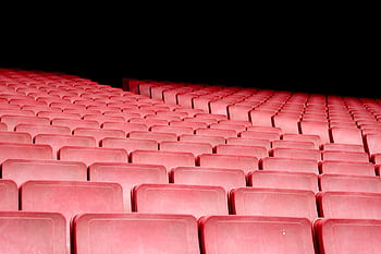 Rows of red seats in an empty auditorium with dramatic lighting. HD wallpaper