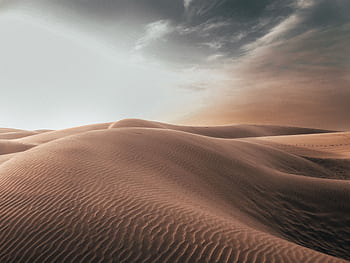 Majestic sand dunes under a dramatic sky, capturing the serenity of the desert at dawn. HD wallpaper