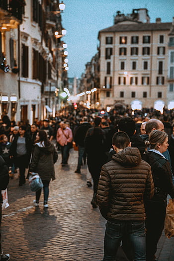 A vibrant street filled with people in the evening, showcasing urban life and city architecture. HD phone wallpaper
