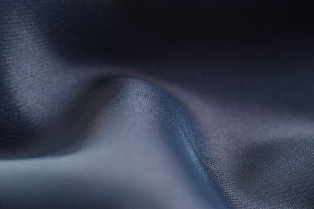 Close-up view of blue fabric showcasing smooth texture and soft wave patterns. HD wallpaper